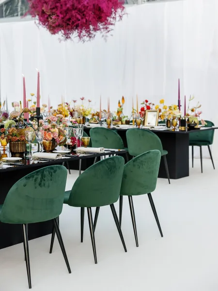 Reception tablescape with modern wedding tablescape styling on black tables, green velvet chairs, taper candles, florals, and white draping backdrop