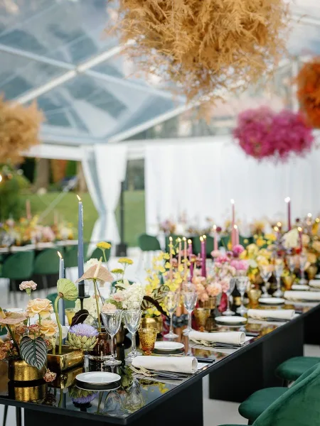 Reception tablescape with wedding head table decor, mixed taper candles and floral centerpieces on a long table under a clear tent on the lawn