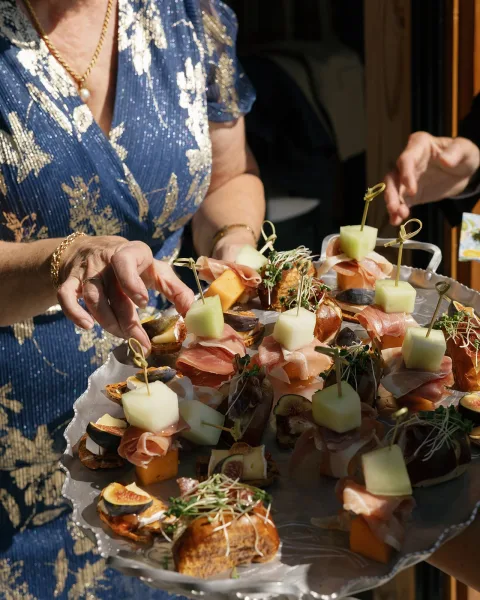 Wedding appetizers and passed hors d'oeuvres arranged on a silver serving tray, presented near a wood doorway with a softly blurred interior.