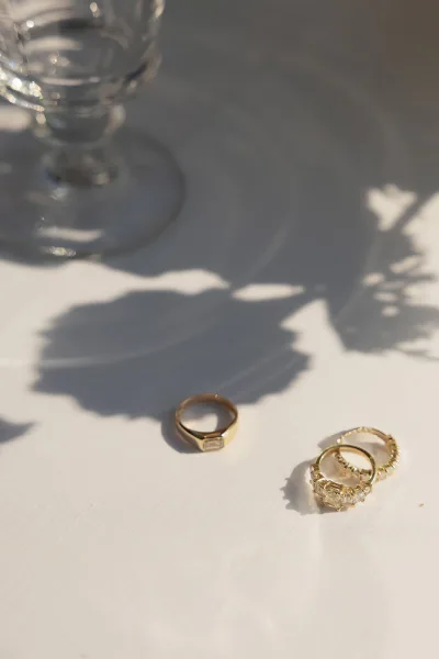 Wedding rings in an engagement ring close-up, gold bands and a solitaire engagement ring arranged with soft glassware bokeh.
