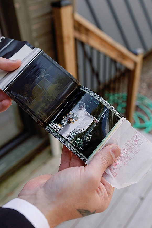 Wedding film photos held in hands with instant film wedding photos prints beside a film cartridge, framed by a border on a wood deck walkway