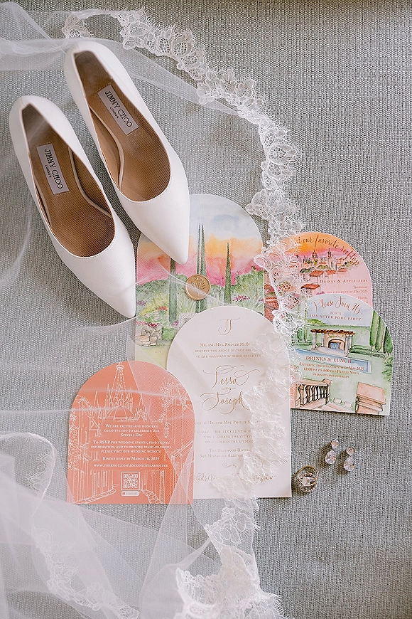 Invitation suite wedding invitation flat lay with RSVP and illustrated cards, bridal shoes, lace veil, rings, earrings, and wax seal on gray linen