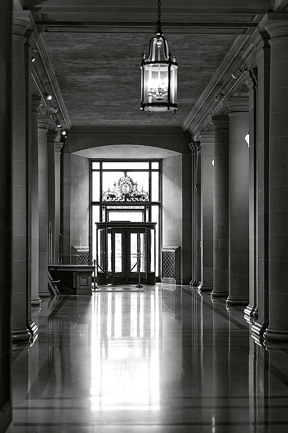 Wedding venue interior with a grand entrance hallway, stone columns and arched entryway, lantern chandelier, and polished floor reflections