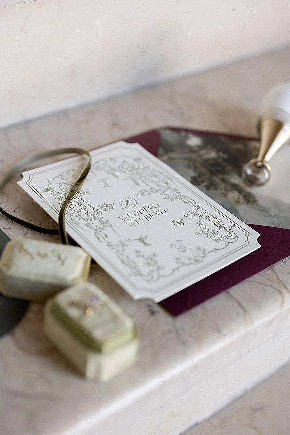 Invitation suite wedding invitation flat lay with botanical cards, wax seal, ribbon, and vintage ring boxes on a marble tabletop