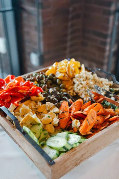 Antipasto platter inspires wedding appetizer ideas, featuring stuffed grape leaves, set against a rustic brick wall backdrop.