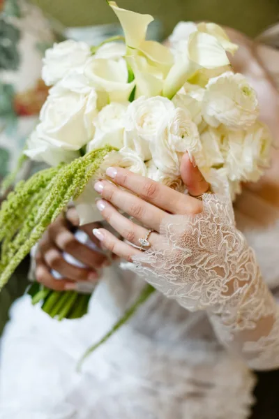 Bridal bouquet, a white calla lily bouquet, showcases an engagement ring nestled among petals against a green backdrop.