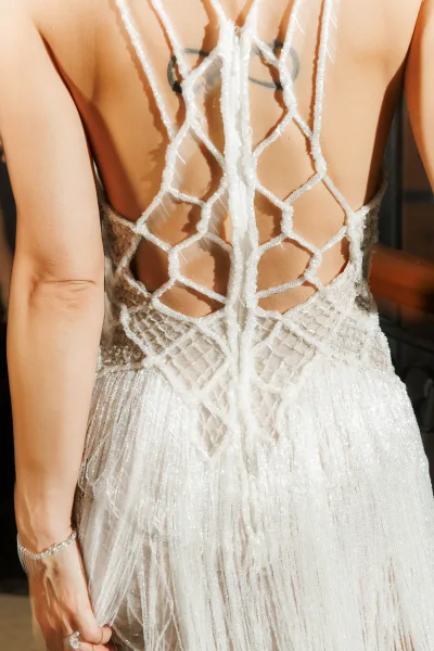 Wedding dress back with illusion back bodice, lace embroidery and beading, spaghetti straps and low low back in sunlit indoor setting by railing