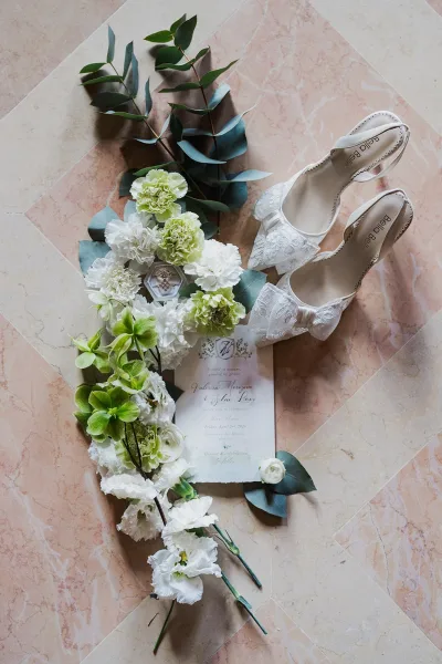 Bridal shoes, lace bridal heels finished with delicate lace bows, styled on a polished marble tile floor.