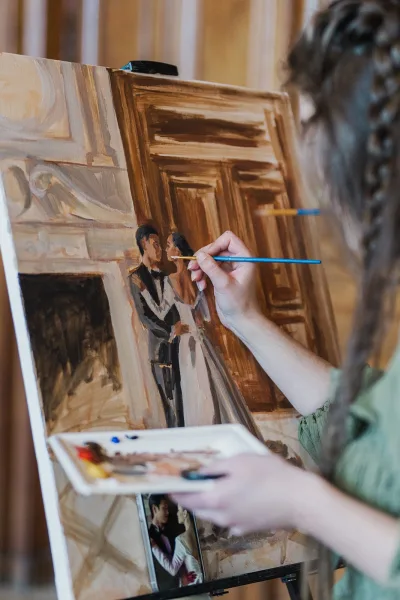 Live wedding painter capturing a reception live painting at an easel in a wood-paneled room, focused on the unfolding wedding scene.