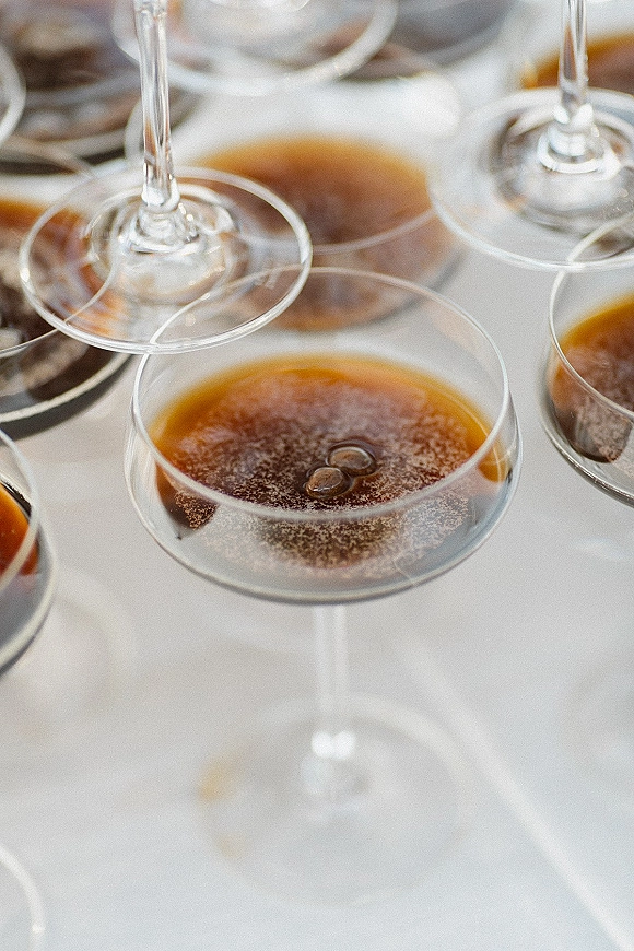 Champagne coupe tower with sparkling wine cascading through vintage glasses on a cocktail tray against a soft white bokeh backdrop