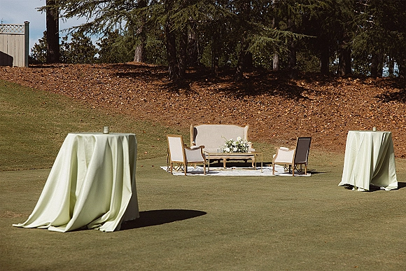 Wedding lounge seating outdoor wedding lounge with vintage sofa, upholstered armchairs, candles and florals on a rug on a grassy lawn hillside