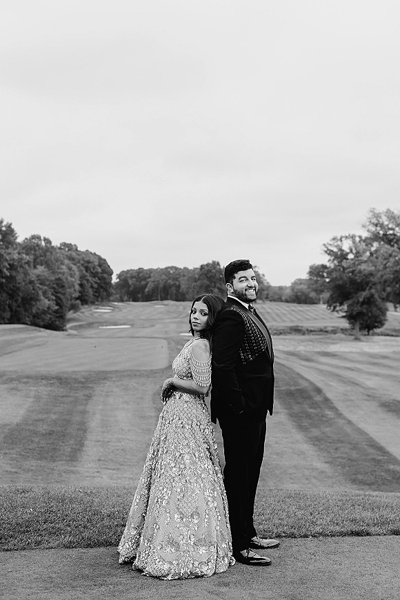 Couple portrait in a black and white wedding portrait, bride and groom back to back on a golf course fairway under overcast sky