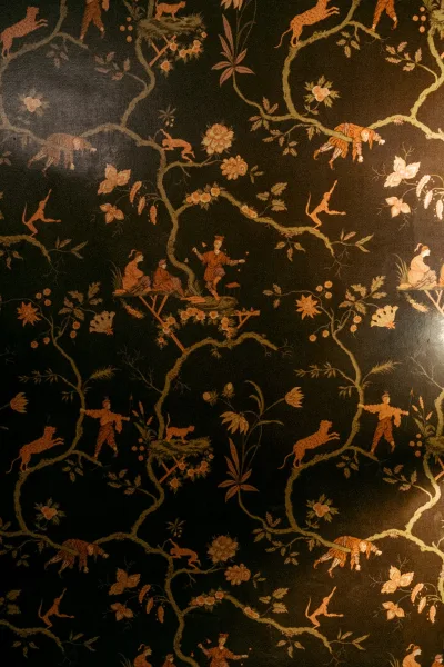 Chinoiserie wallpaper styled as a botanical wall mural featuring playful monkeys across an intricate pattern with scenic chinoiserie motifs.