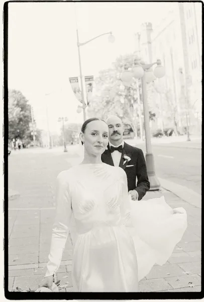Couple portrait, a city wedding portrait on a tree-lined street, bride in a long-sleeve gown and groom with a bow tie.