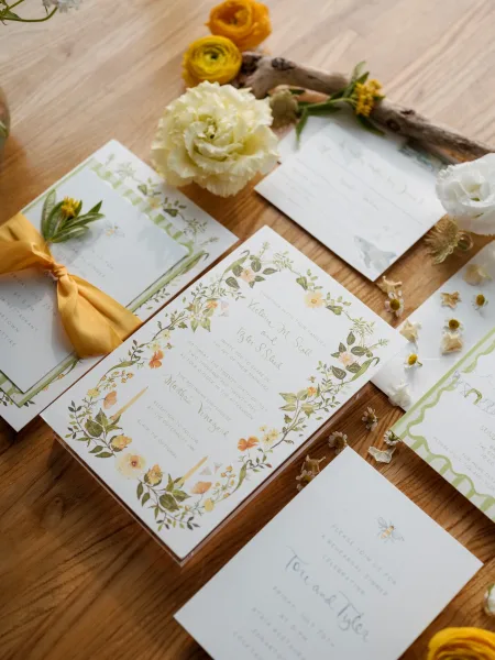 Invitation suite with botanical wedding invitations, RSVP and detail cards, silk ribbon bow and wax seal, styled with flowers on wood tabletop