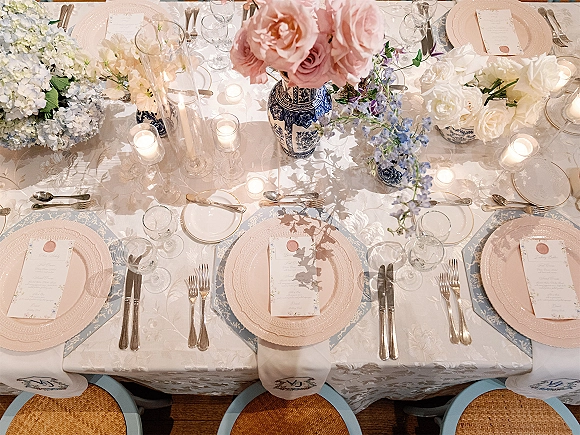 Reception tablescape wedding table setting with blue-and-white vases, blush plates, wax-sealed menus, and candlelight on patterned linens