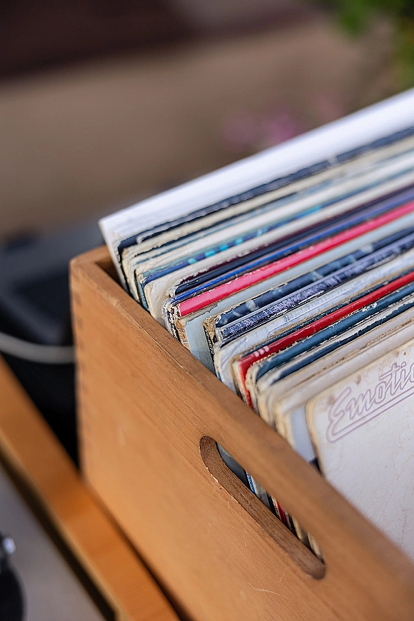 Record collection in a vinyl record crate, album sleeves and vinyl records neatly stored in a wooden crate with blurred indoor furniture behind