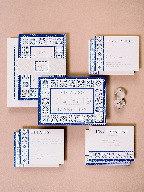 Invitation suite with blue tile wedding invitation cards, RSVP and tea ceremony inserts, plus ring box and engagement ring on neutral tabletop