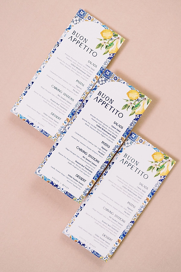 Wedding menu cards with an Italian wedding menu design, blue and white patterned border, and lemon illustration on a blush backdrop