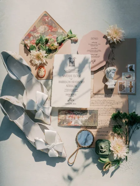Invitation suite with a handmade paper invitation on a light linen surface, styled beside a green velvet ring box