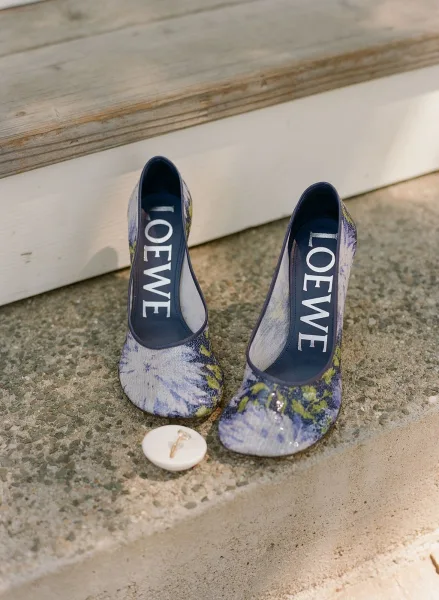 Wedding shoes with something blue floral heels and personalized soles on a concrete step by a wooden porch with white siding