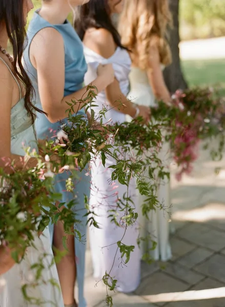 Bridesmaid bouquet with greenery bridesmaid bouquet styling, trailing vines held by bridesmaids in pastel dresses on a tree-lined walkway