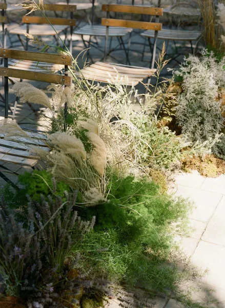 Ceremony seating with outdoor wedding chairs lined on a stone patio aisle, styled with greenery and pampas grass meadow florals