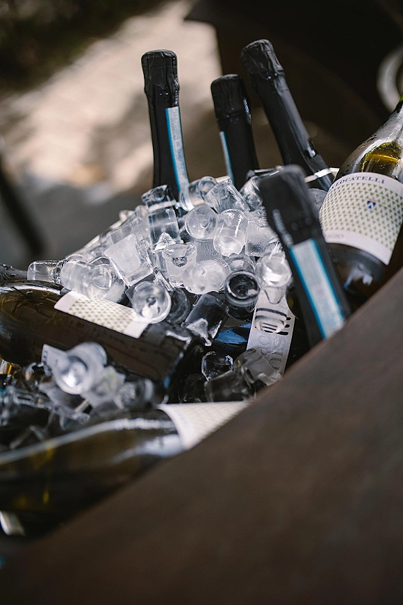 Champagne on ice in a champagne bucket, bottles nestled among ice cubes with visible labels in soft outdoor light