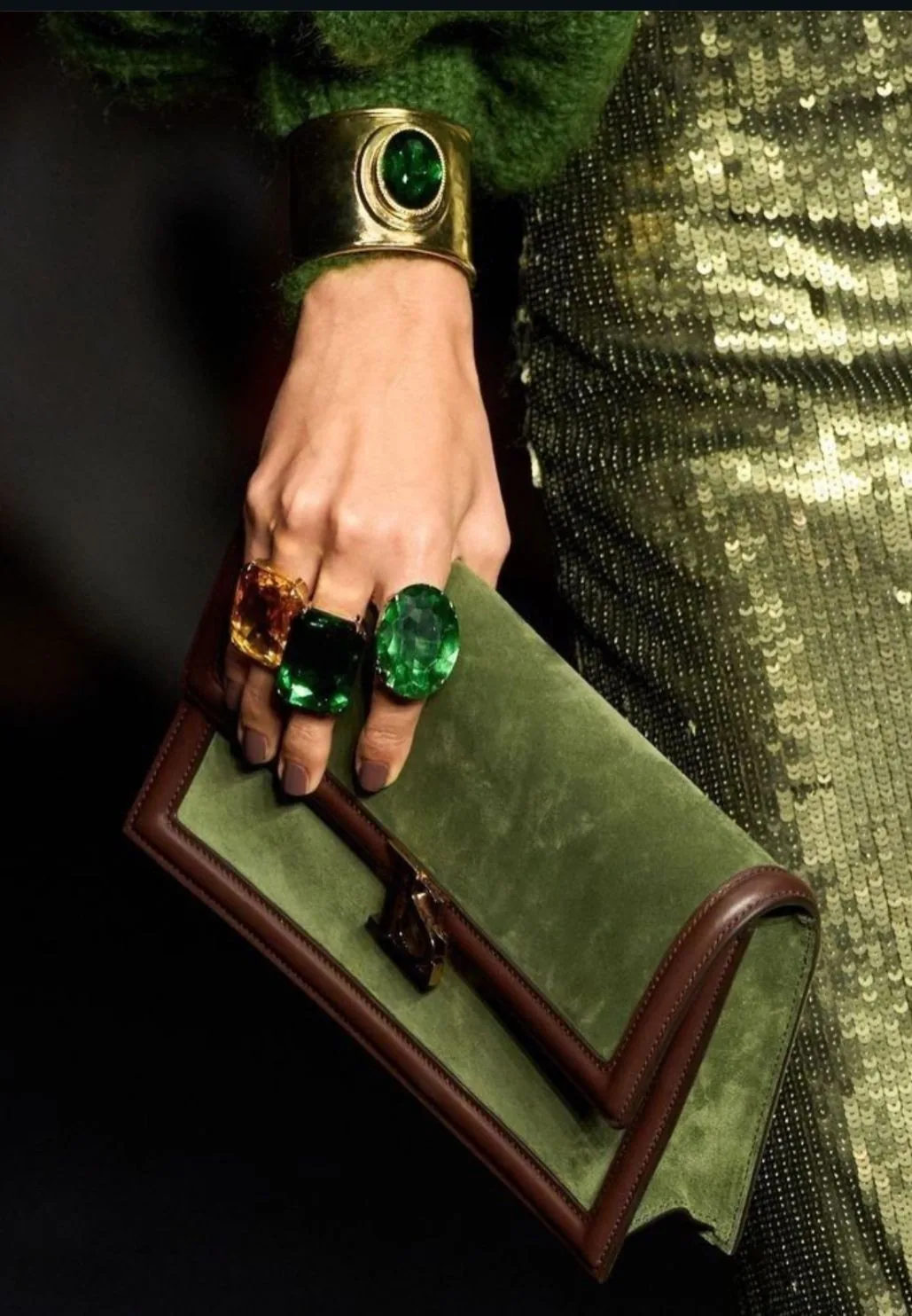 Green suede clutch, emerald cocktail rings and a gold cuff against a sequinned olive skirt