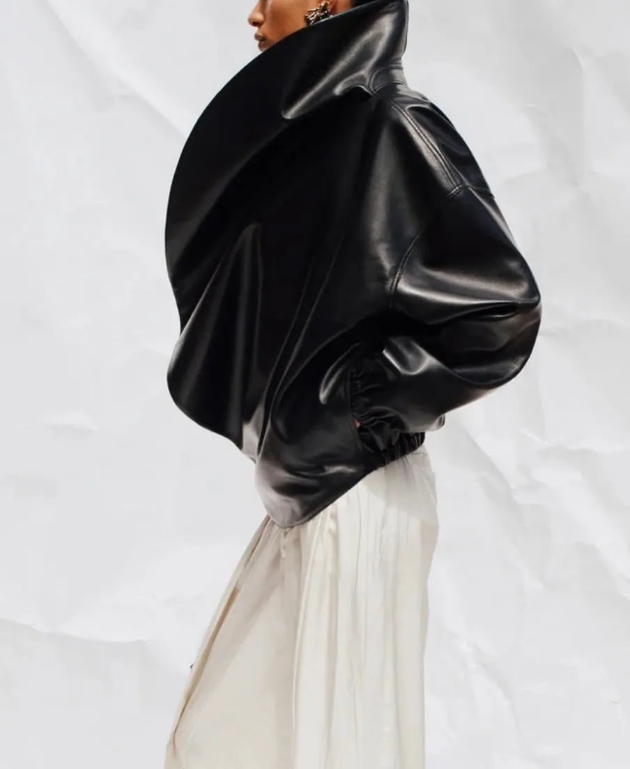 Sculptural black leather jacket worn over a white satin skirt