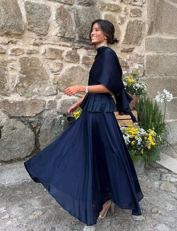 Navy blouse and flowing navy maxi skirt against a stone wall
