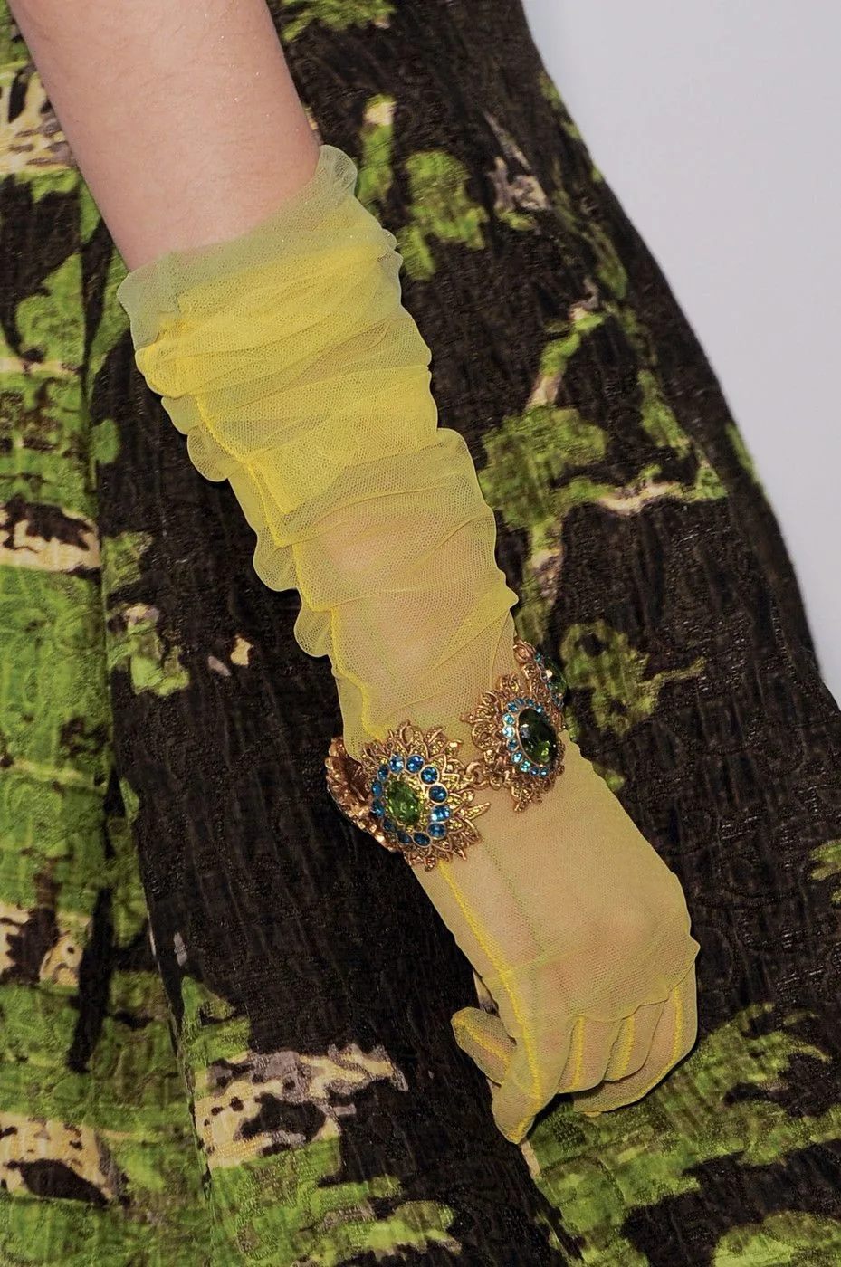Sheer chartreuse opera glove with a jewelled cuff over a dark floral jacquard