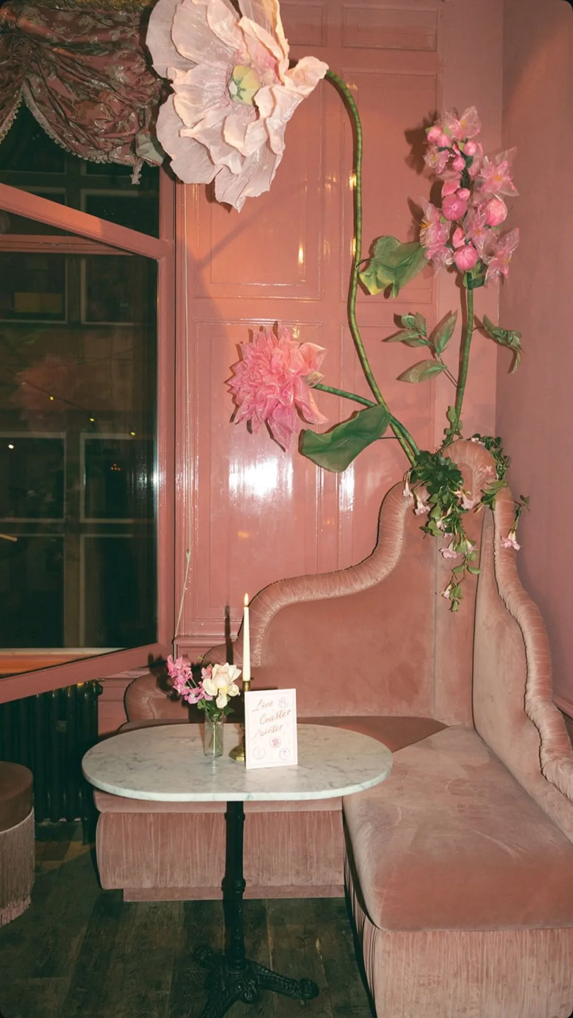 Blush pink lounge with oversized paper flowers and a marble bistro table
