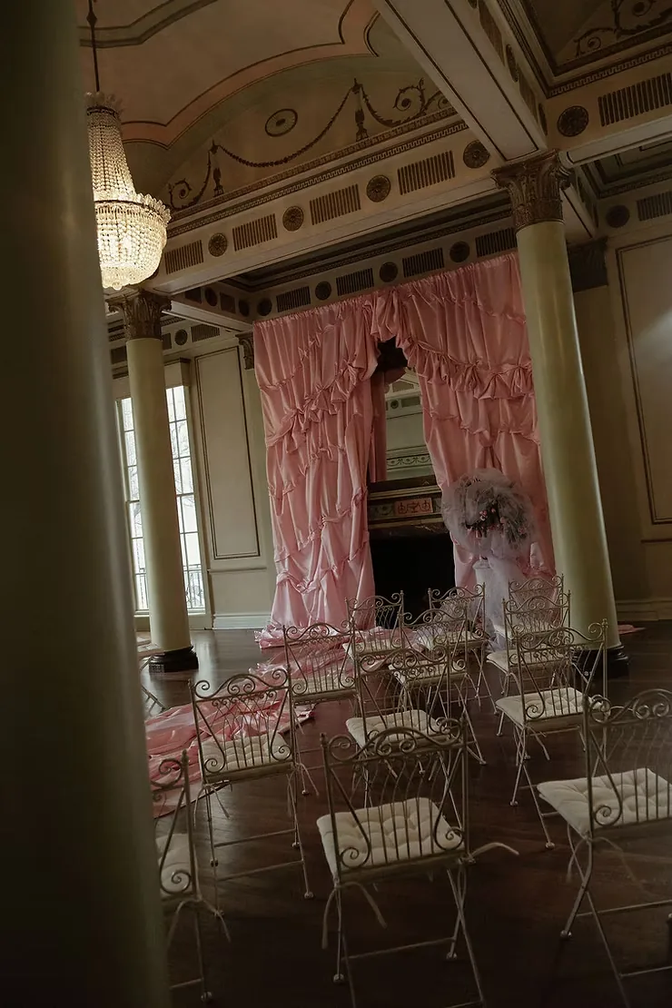 Palace ballroom with pink ruched curtains, a chandelier and wrought-iron chairs