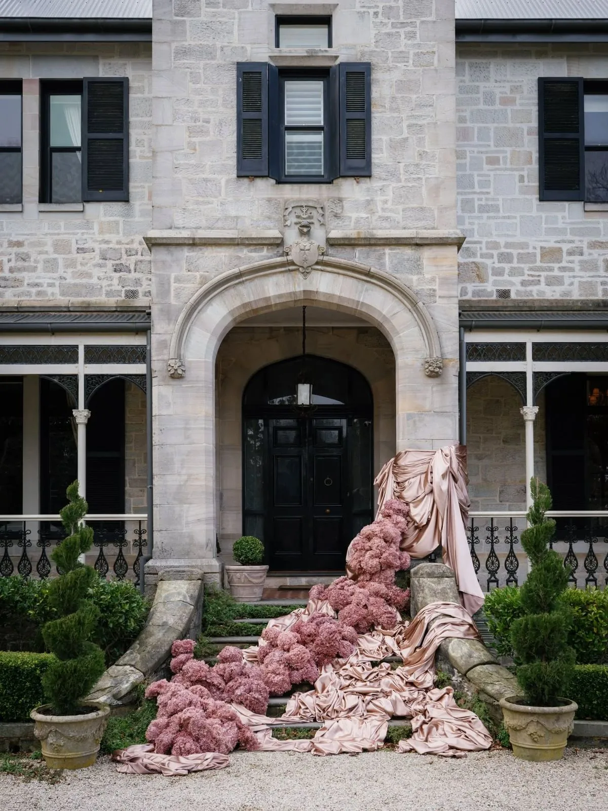 Pink floral installation cascading down the front steps of a stone manor