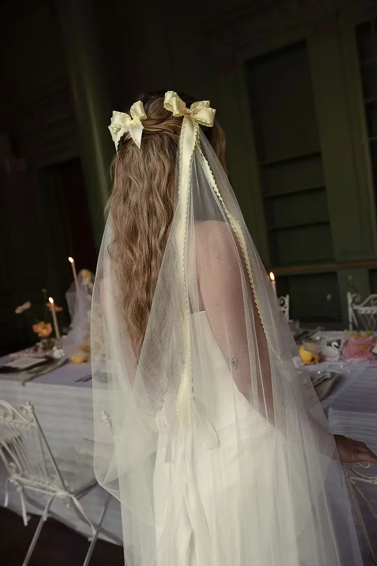 Bride with long waves and ivory bows tied into her veil