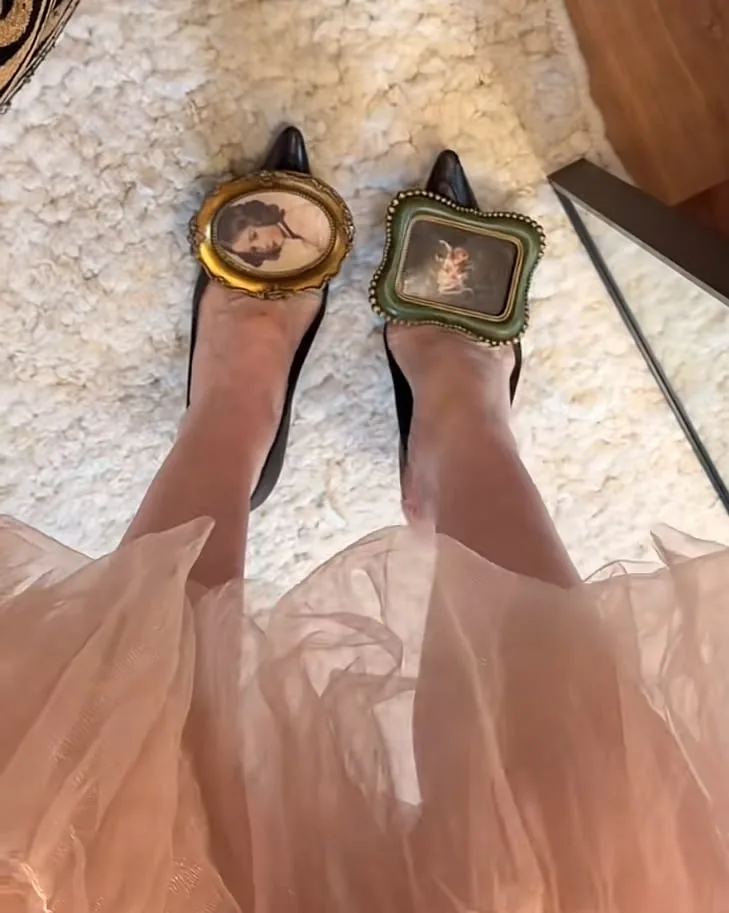 Black pointed heels with framed miniature portraits over a blush tulle skirt