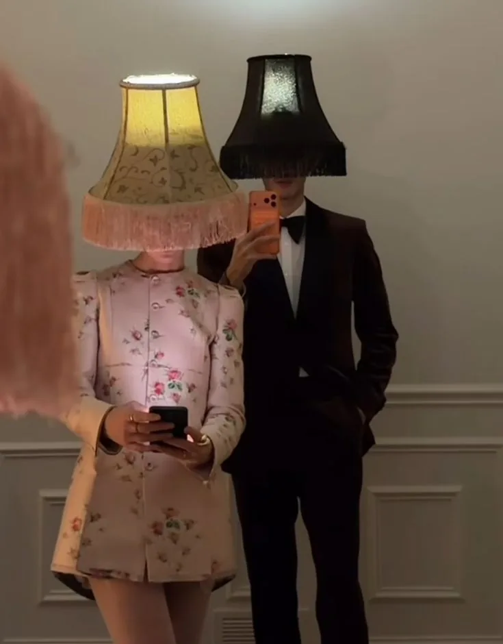Two guests wearing fringed lampshades over their heads