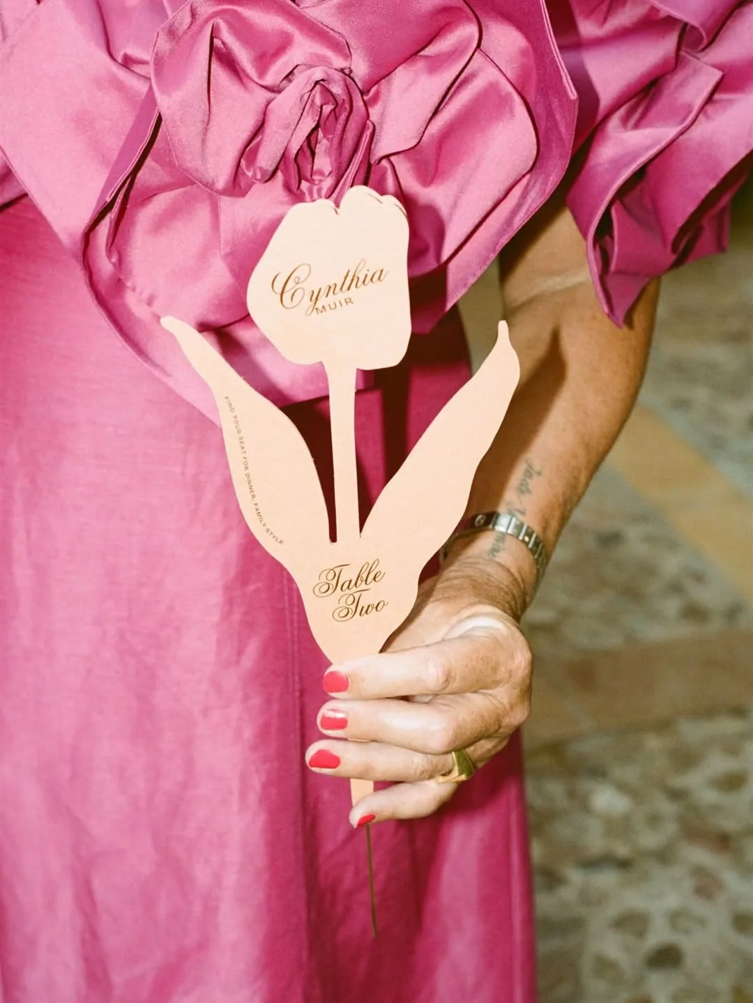 Guest in a pink taffeta dress holding a tulip-shaped place card