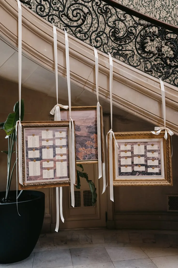 Seating chart in gilt frames hung from a wrought-iron staircase
