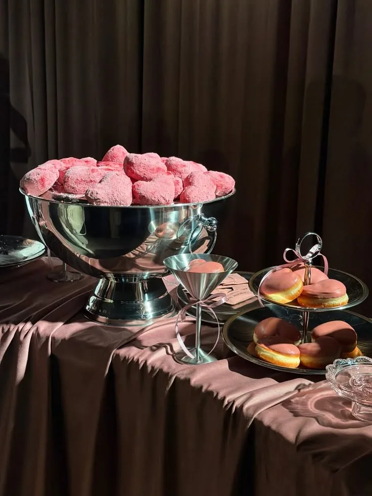 Silver punch bowl of pink meringues on a chocolate velvet table