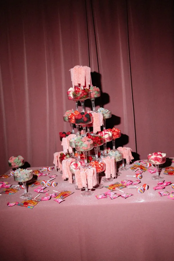 Tiered stand of pink desserts on a pink table under rose velvet curtains