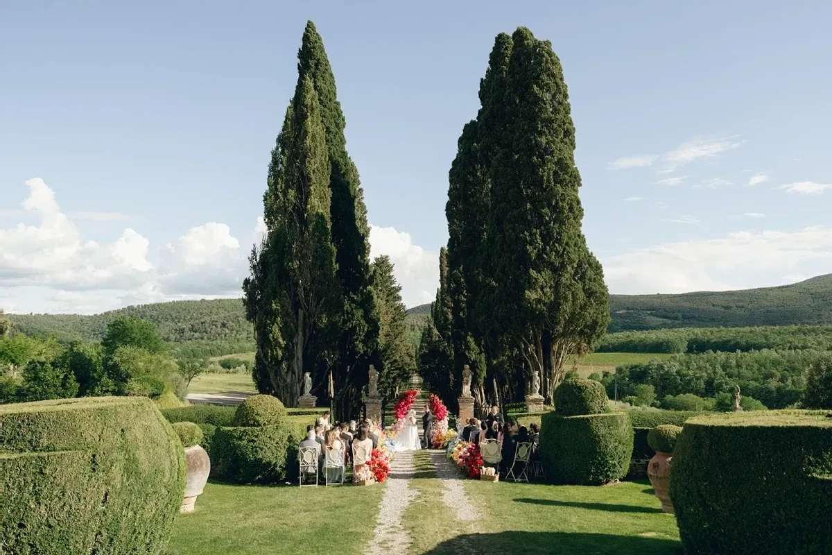A wedding ceremony setup at an estate venue in Tuscany with Cypress trees in the background.