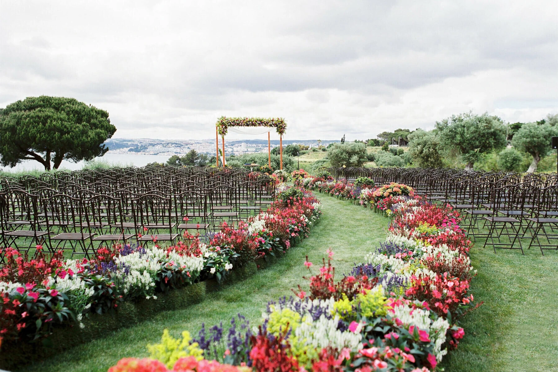 Vibrant multi-colored outdoor wedding ceremony aisle set up in a garden