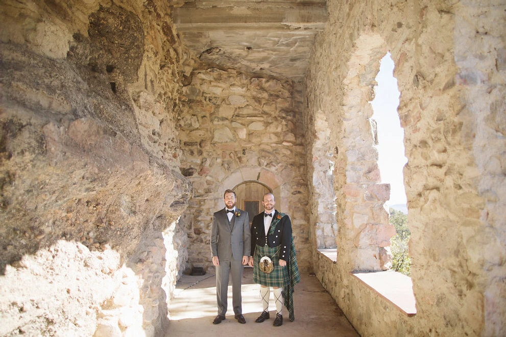 Castle Wedding Venues: Two grooms smiling at a castle property in Sedalia, Colorado.