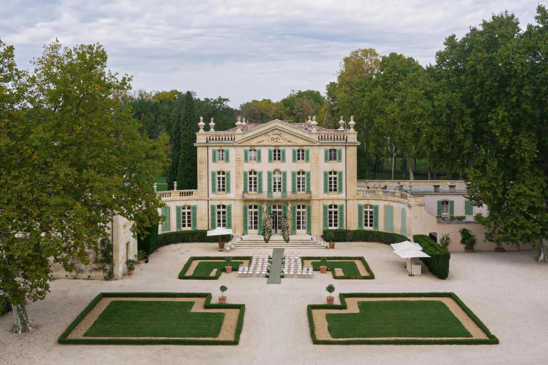 Castle Wedding Venues: A chateau in France surrounded by trees with manicured lawns and green-shuttered windows.