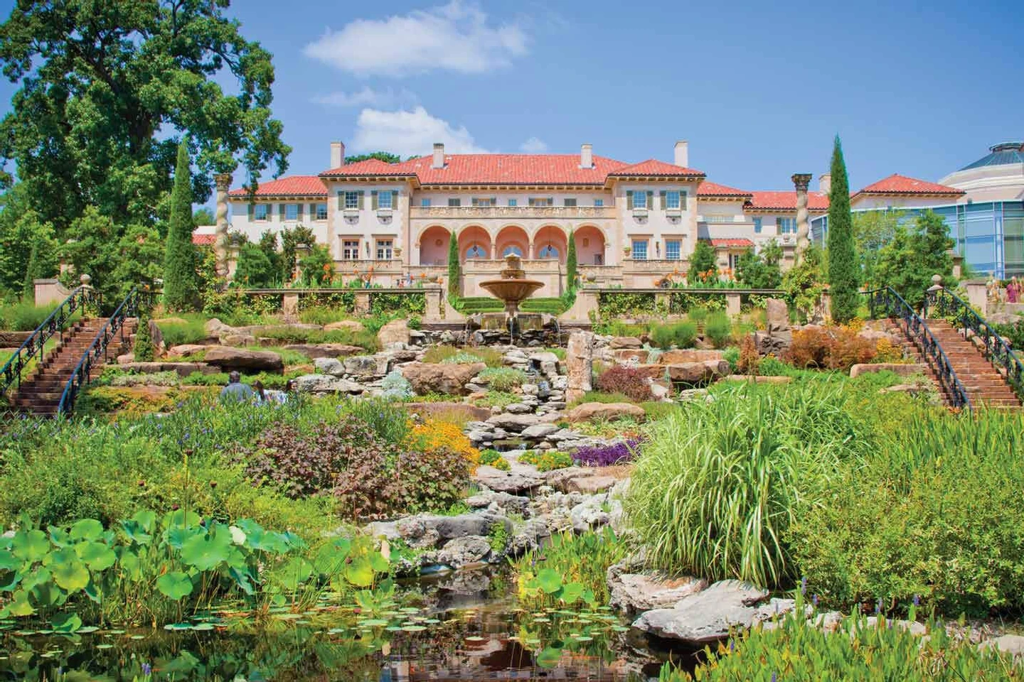 Celebrity Wedding: A museum in Tulsa surrounded by lush gardens and a prominent fountain leading up to the building.