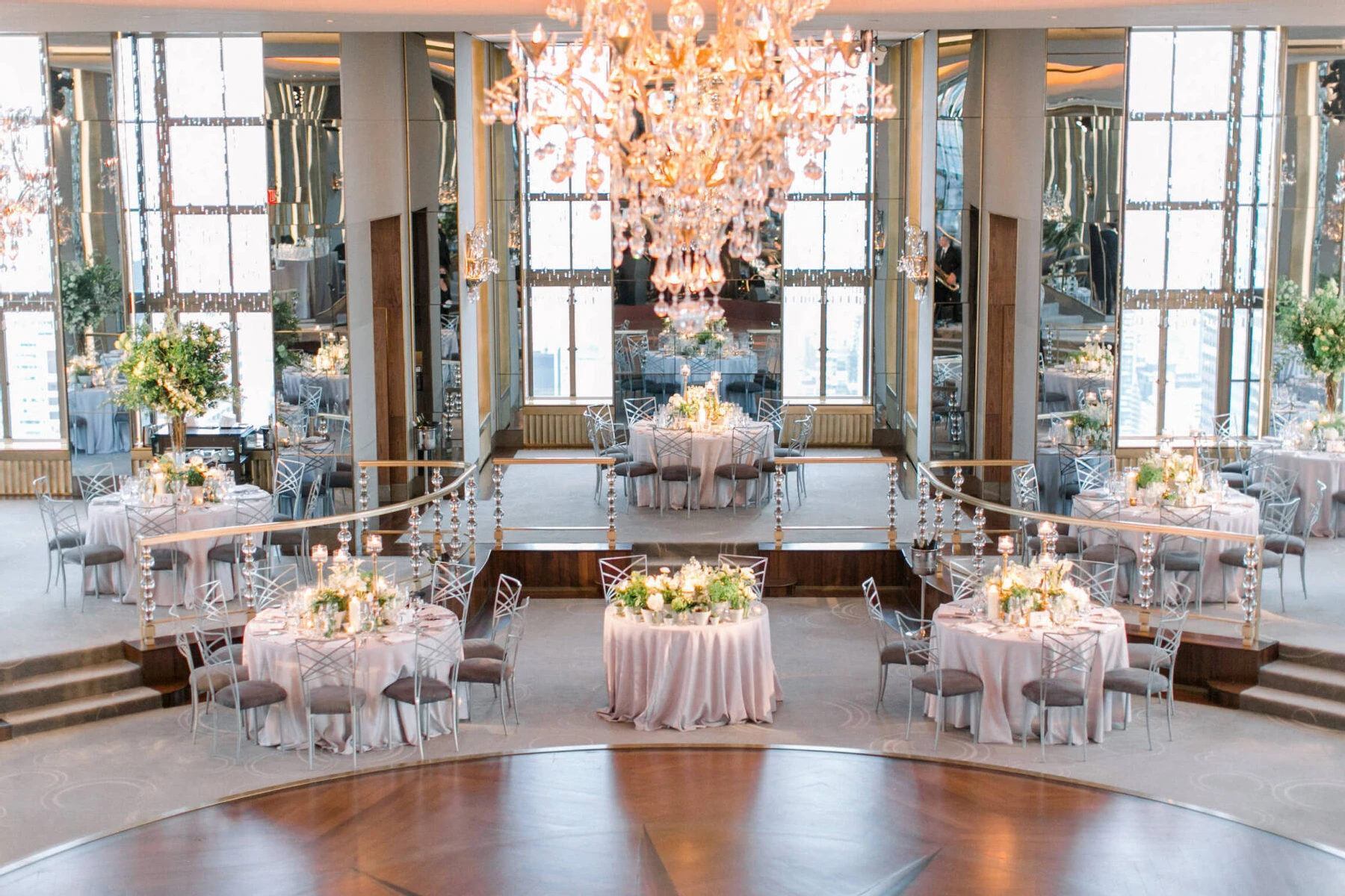 Celebrity Wedding: An indoor reception setup with round tables and a chandelier overhead at the Rainbow Room ballroom in New York City.