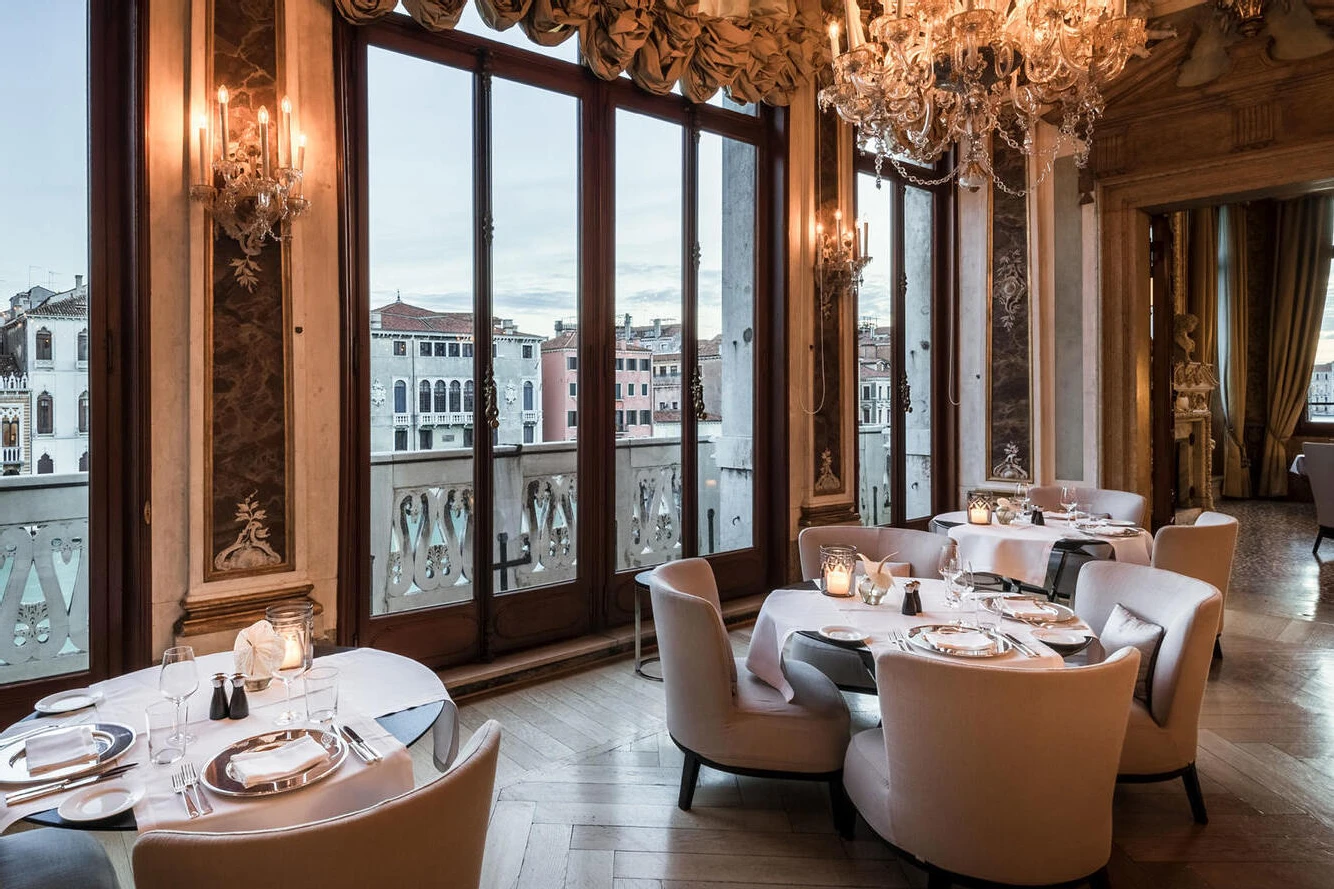 Celebrity Wedding: An indoor reception setup with tables, a chandelier, and the canals in Venice just outside.