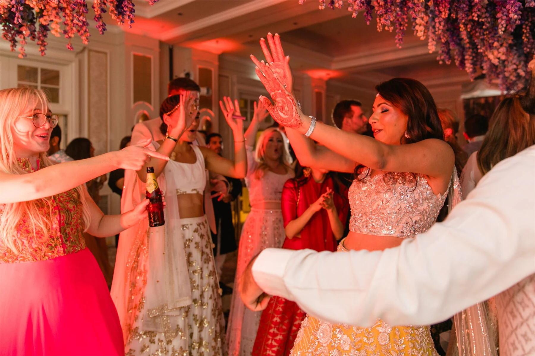 A bride and her friends dance during her colorful countryside wedding reception.